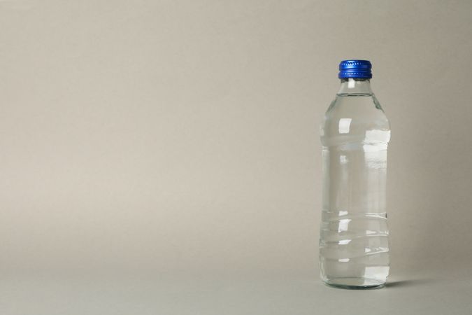 Plastic water bottle in beige room with copy space