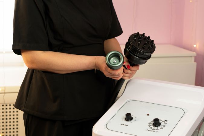Therapist holding two cavitation device attachments near control panel