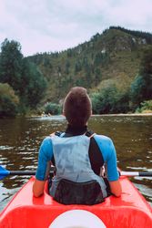 Female kayaking with paddle in raised hands