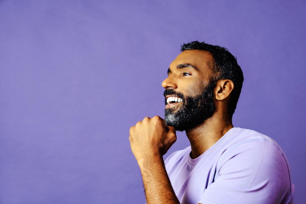 Side view of contemplative male in purple t-shirt looking to the side, copy space