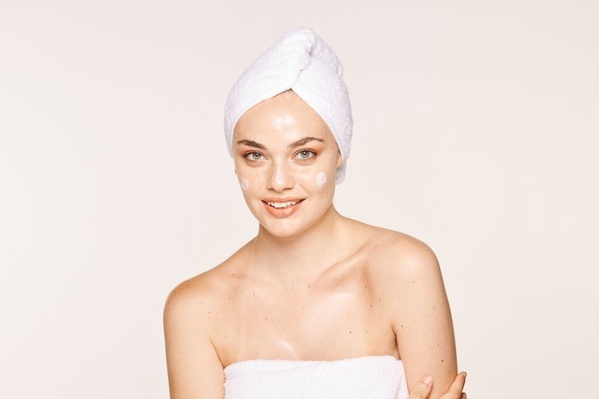 Delighted female with radiant skin applying cream