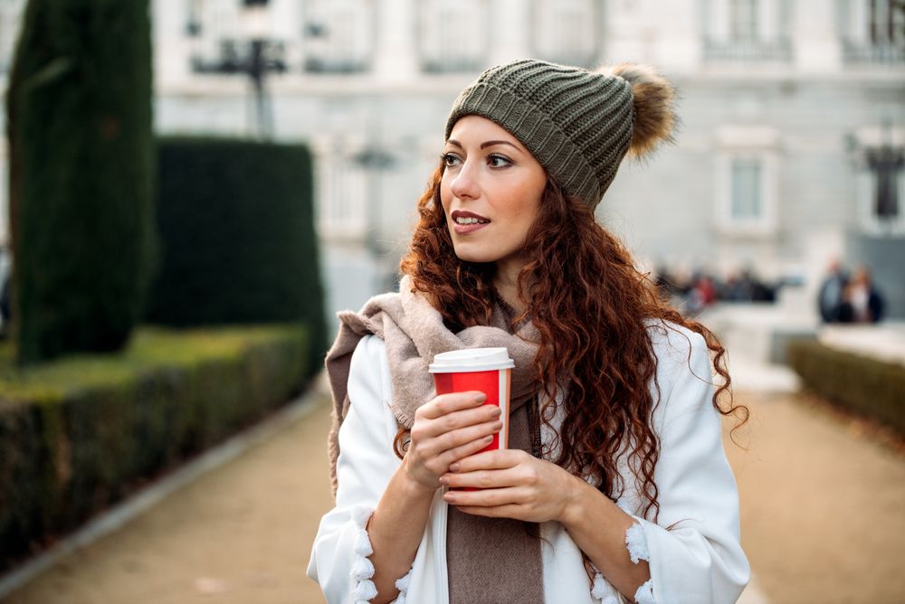 Woman drinking coffee in the streets of Madrid on winter
