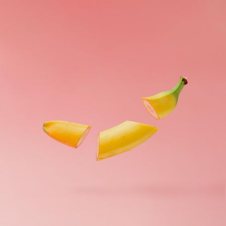 Banana slices on pastel pink background with copy space