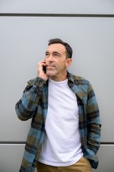 Smiling man talking on smartphone and looking away