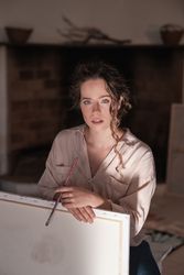 Portrait of young female artist with hands on canvas