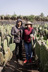 Mother and son are posing in a nopal field while working during the harvest