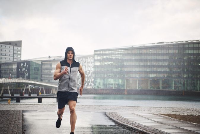 Muscular man in rain running in the rain