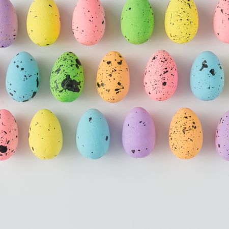 Rows of pastel Easter eggs on light background
