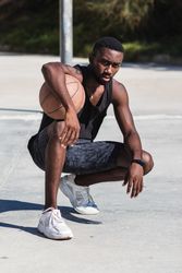 Confident Black sportsman on basketball court in summer