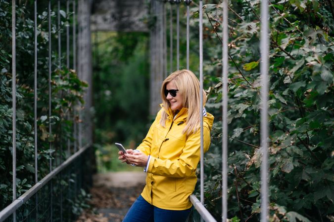Happy female traveler taking selfie on suspension bridge in summer