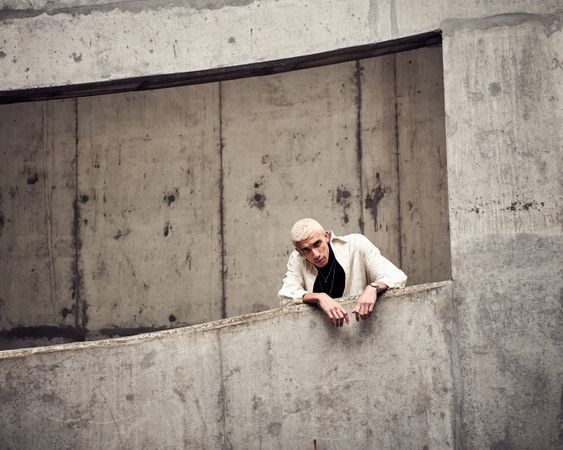 Young man leans over the edge of cement structure