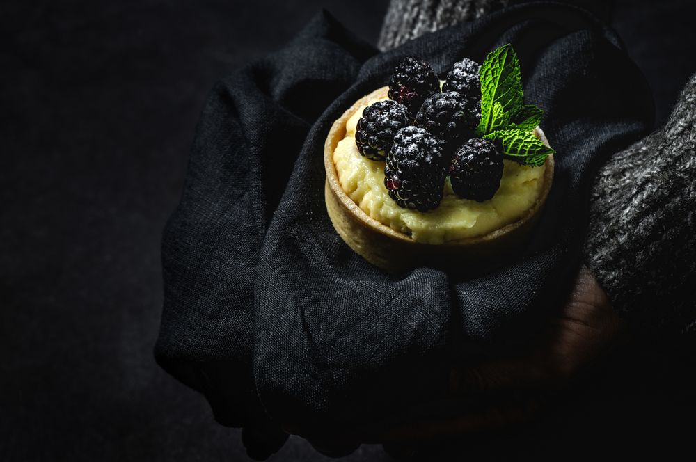 Hand holding a blackberry tartlet