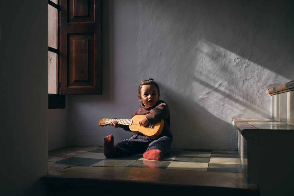 Girl playing ukulele on floor at home