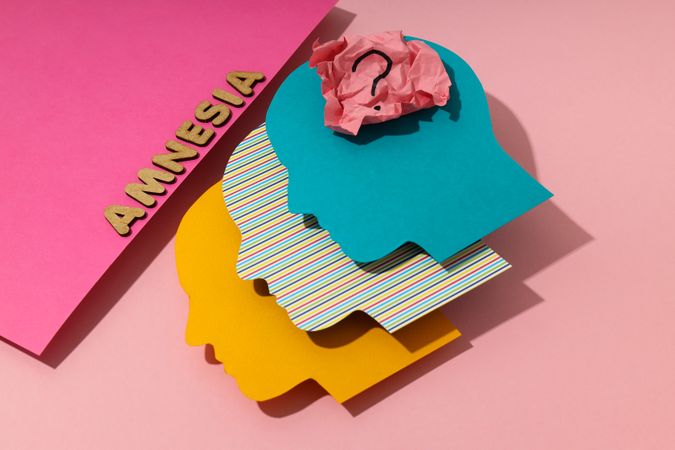 Colorful head shaped heads on pink background with the word “Amnesia”