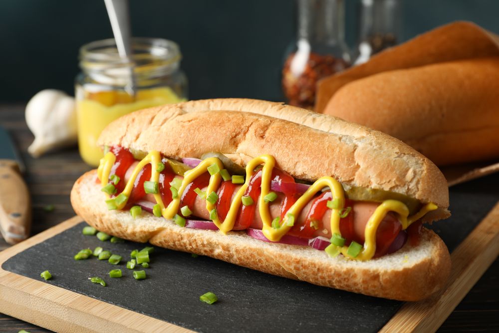 Tasty hot dog and ingredients on wooden background
