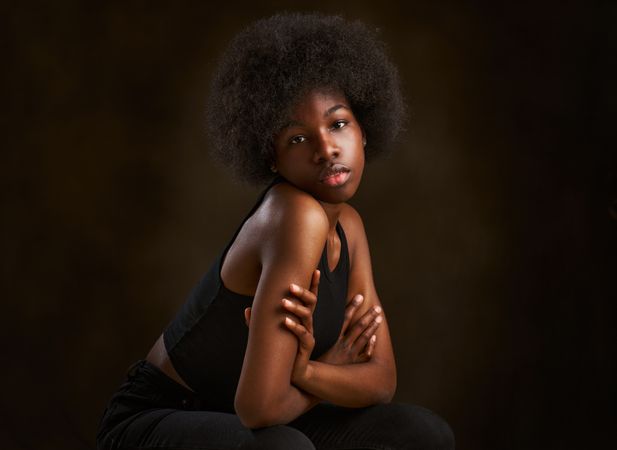 Happy young woman with afro hairstyle sitting with arms folded