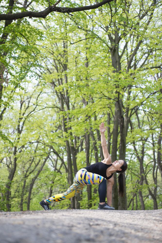 Woman in colorful exercise gear stretching in the forest