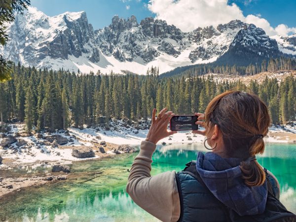 Woman in down vest taking photo of amazing landscape