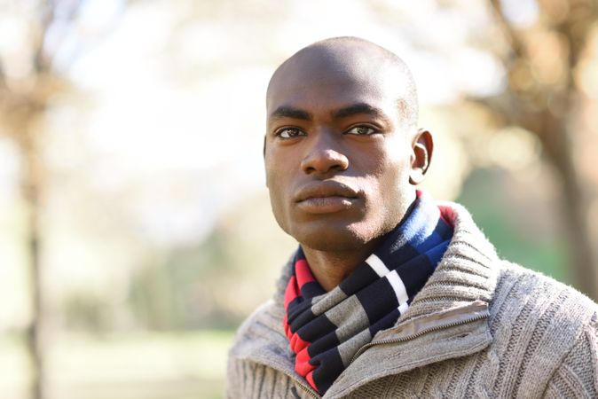 Serious male in sweater standing in park