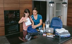 Mother preparing emergency backpack with her daughter