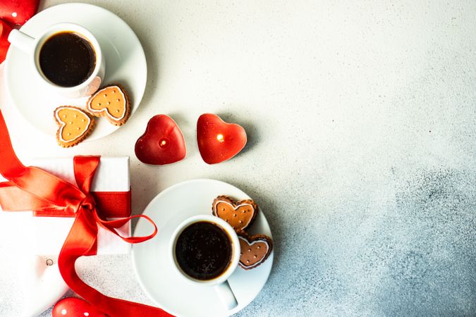 Top view of two coffees with iced cookies and heart candles with space for text