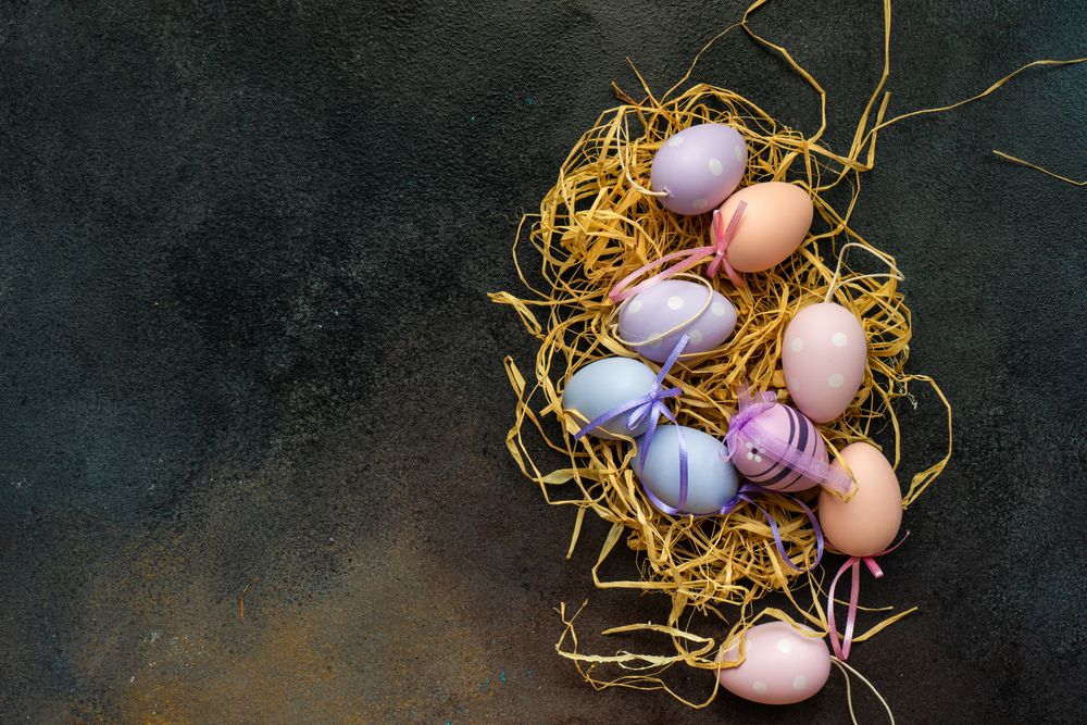 Pastel Easter decorations in straw on grey table