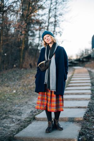 Red haired woman on pavement near trees on a cold day