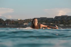 Smiling woman on surf board floating on water