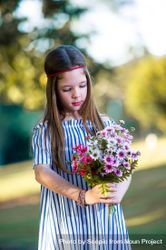 Girl in blue striped dress holding a bouquet of flowers standing outdoor 42xGg0