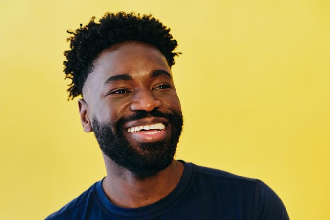Black man smiling in yellow studio shoot