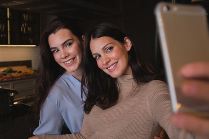 Smiling women taking selfie in kitchen