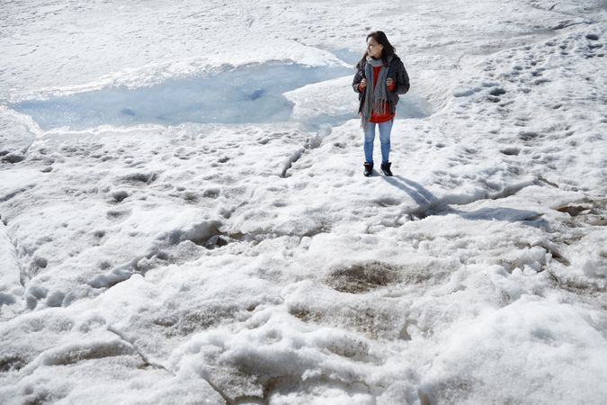 Young adult woman outdoors travelling with backpack in icy lands