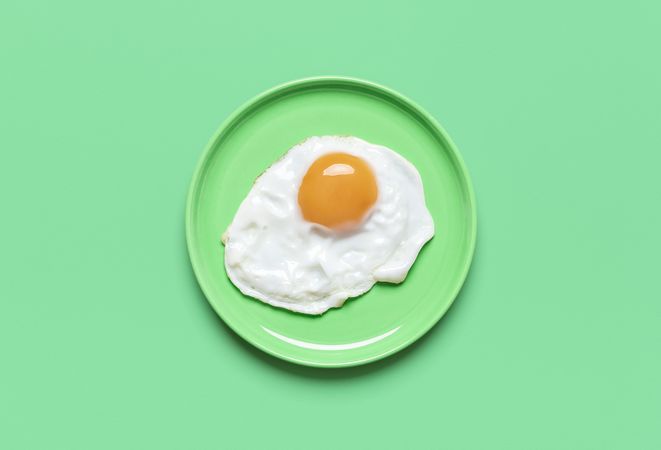 Fried egg on green plate, view from above