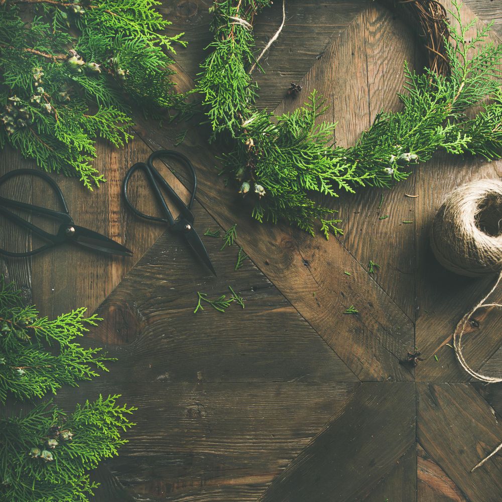 Fir wreath being built on wooden table, with scissors, and cord