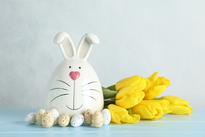 Decorated bunny and Easter eggs on table against color background. Space for text