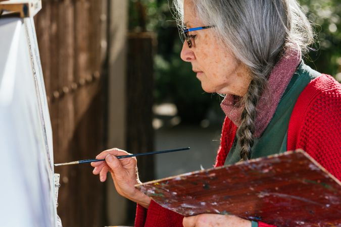 Mature woman painting on canvas in garden