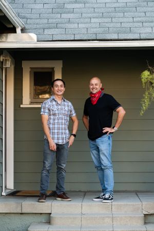 Married couple standing in front of their house on the porch smiling and looking at camera