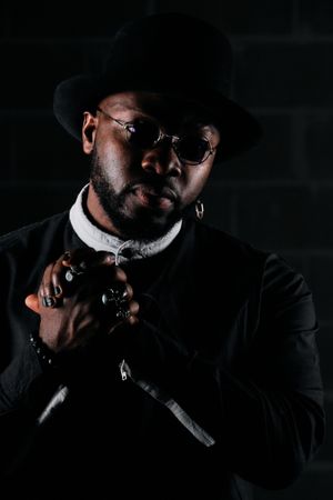 Stylish Black man in hat holding hands together