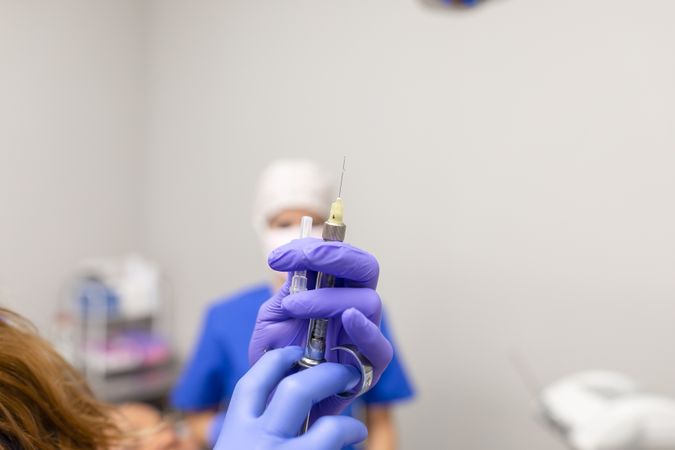 Close up view of the hands of a female dentist holding a syringe
