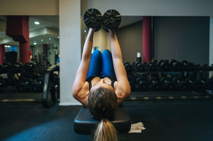Woman lifting dumbbells on bench