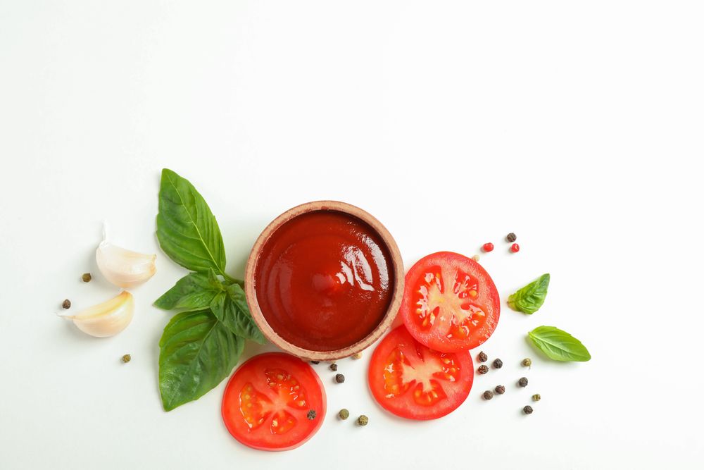 Flat lay composition with fresh cherry tomatoes slices, basil, pepper, garlic and sauce on plain background, space for text. Ripe vegetables