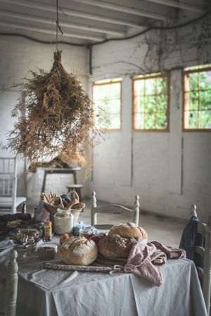 Fresh bread on served table and bunch of dry plant hanging on thread