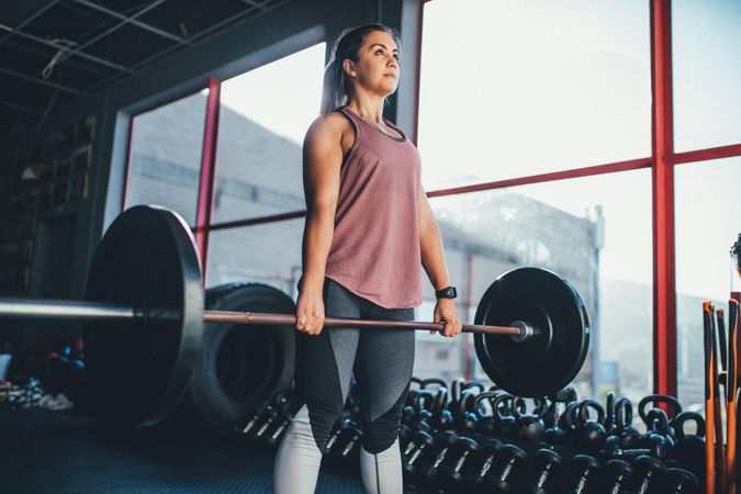 Woman in gym standing holding a weighted barbell