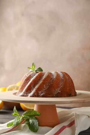 Cake with powder sugar and mint on wooden background, space for text