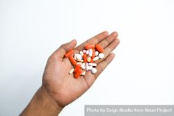 Hand holding variety of colorful medication and vitamins with plain background 4MGDjy