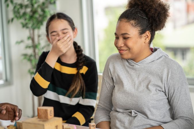 Two female students laughing over fallen building blocks