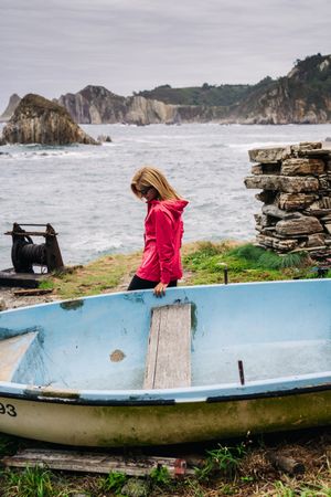 Woman in old blue on seashore washing by foamy waves