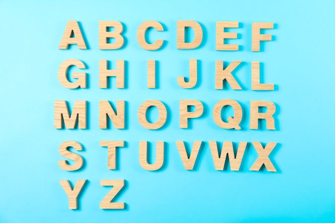 Wooden letters of English alphabet on color background, top view