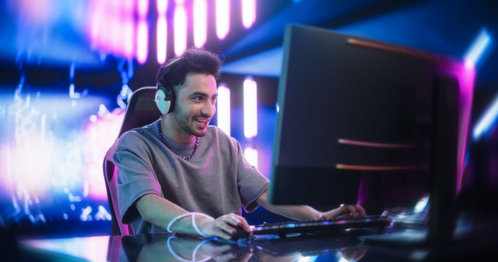 Portrait of a Happy Young Man in Headphones Talking with Friends Online on a Computer.