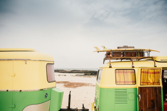 Colorful minibus with trailer parked on sandy shore in sunny day